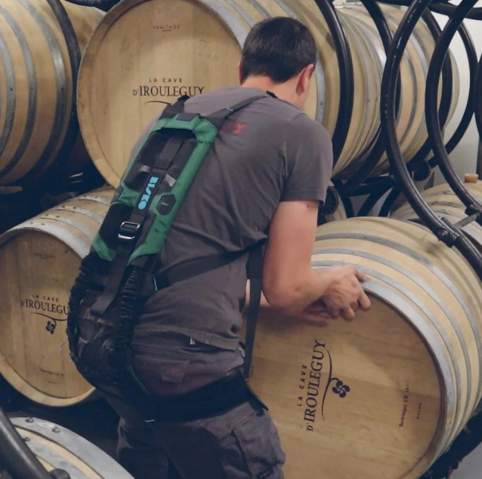 Manutentionnaire dans une cave à vin portant un exosquelette Bisko